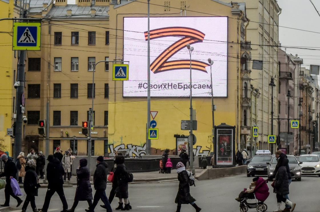Pedestrians cross a street in front of a billboard displaying the symbol &quot;Z&quot; in the colors of the ribbon of St. George and a slogan reading: &quot;We don&#039;t give up on our people,&quot; in support of the Russian armed forces, in St. Petersburg, Russia, March 7, 2022. (AFP Photo)