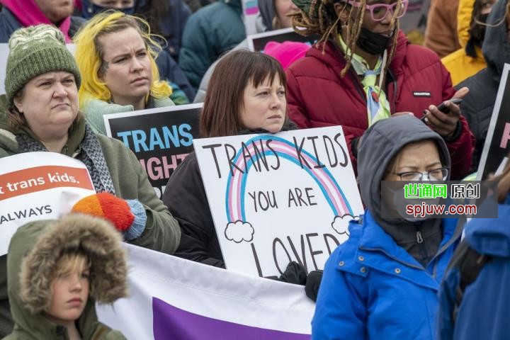 Protesters hold up signs in support of trans children.